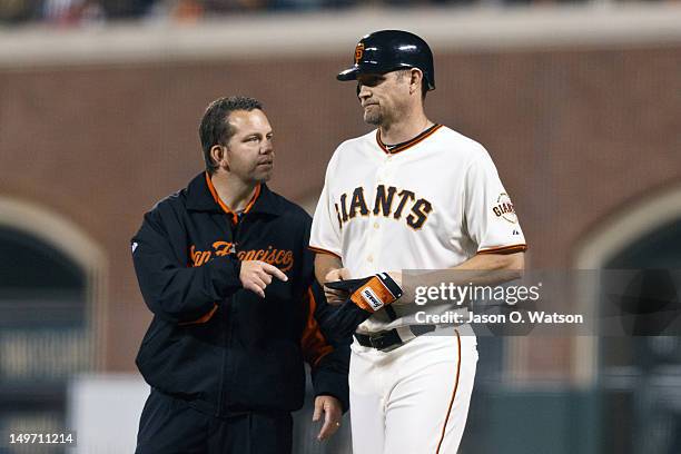 Aubrey Huff of the San Francisco Giants talks with trainer Dave Groeschner after injuring his knee on a play at first base against the New York Mets...