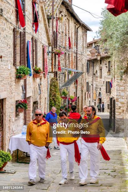 some bearers of the festa dei ceri walk along a medieval stone alley of gubbio in umbria - italiaanse etniciteit stockfoto's en -beelden