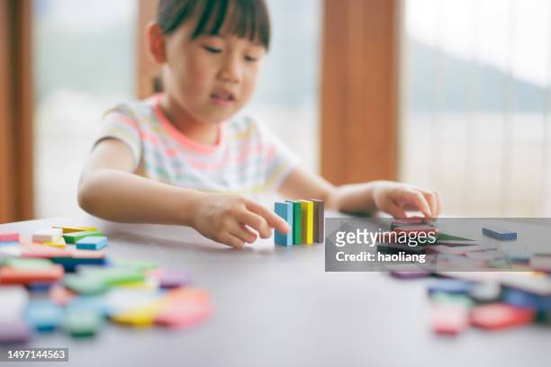 young girl plays domino tiles falling game at home - girl looking down stock pictures, royalty-free photos & images