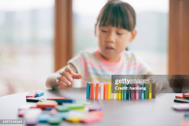 young girl plays domino tiles falling game at home - girl looking down stock pictures, royalty-free photos & images