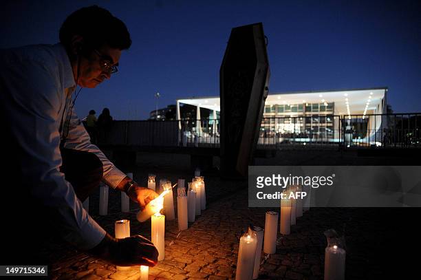 Demonstrator lights up a candle during a protest in front of the Supreme Court, where the trial known as 'mensalao' is being held, in Brasilia,...