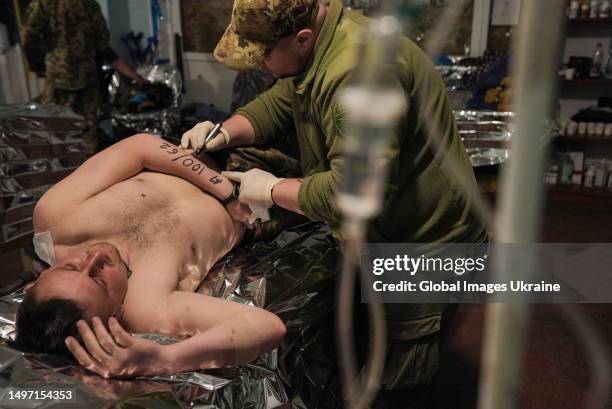 Combat medic writes on the arm of Ukrainian soldier with severe post-concussion syndrome his blood pressure readings at the time of the first...