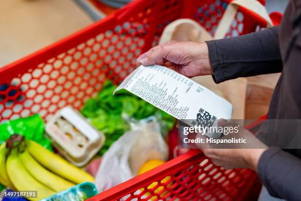 nahaufnahme einer nicht wiederzuerkennenden kundin, die nach dem kauf von lebensmitteln im supermarkt ihre quittung überprüft - paying supermarket stock-fotos und bilder