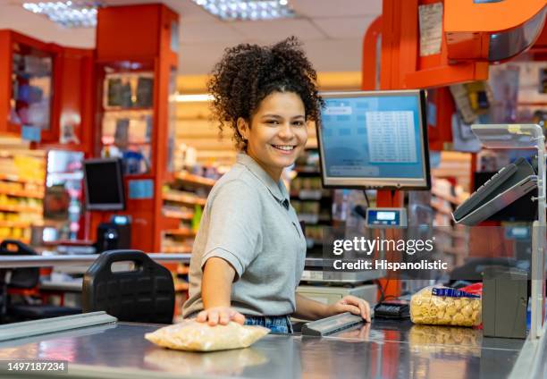 retrato de un joven cajero alegre frente a la cámara sonriendo mientras escanea productos para un cliente - tienda del vecindario fotografías e imágenes de stock