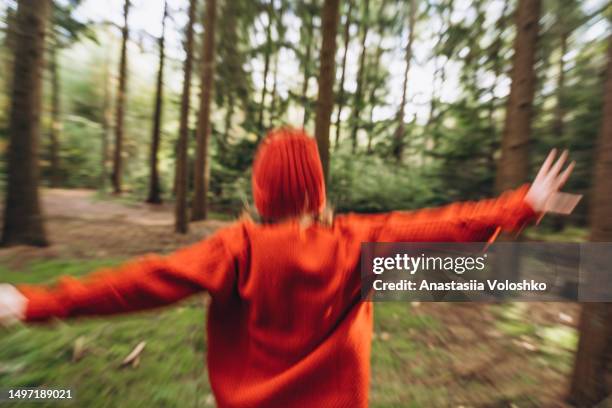 a red-haired girl in a red sweater in a walk in the pine forest in autumn. motion picture out of focus - bokeh love stock pictures, royalty-free photos & images