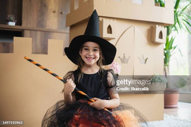 kleine hexe spielt rollenspiel zu hause mit schloss aus pappe - bühnenkostüm stock-fotos und bilder