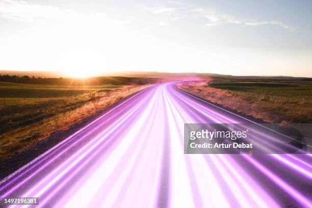 dynamic neon trails flowing in majestic road with golden hour light. - light beam stock pictures, royalty-free photos & images