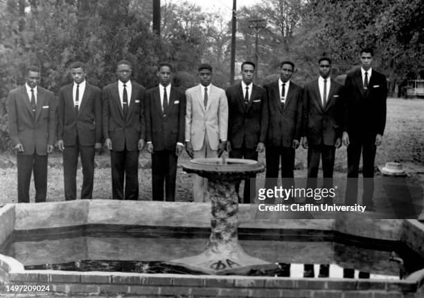 Members of Alpha Phi Alpha fraternity standing in front of a fountain with their logo at Claflin University in Orangeburg, South Carolina in the...