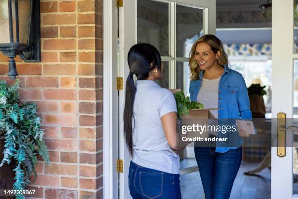 woman receiving a delivery person with her order of groceries - opening a box stockfoto's en -beelden