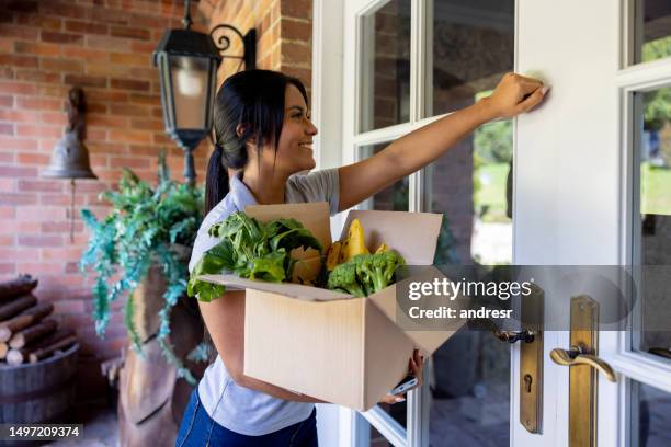 addetto alle consegne che bussa alla porta mentre consegna generi alimentari freschi - bussare foto e immagini stock