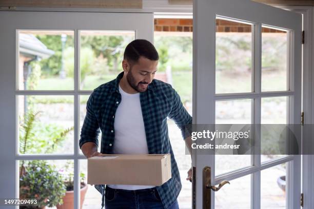 happy man receiving a package at home - receiving hands stock pictures, royalty-free photos & images