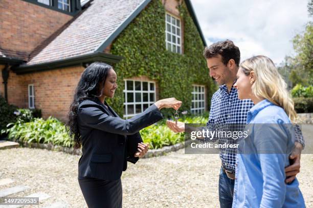 agente immobiliare che consegna le chiavi della loro nuova casa a una coppia - tasto-di-computer foto e immagini stock