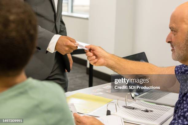 polling place volunteer helps the unrecognizeable adult check in - drivers license stock pictures, royalty-free photos & images