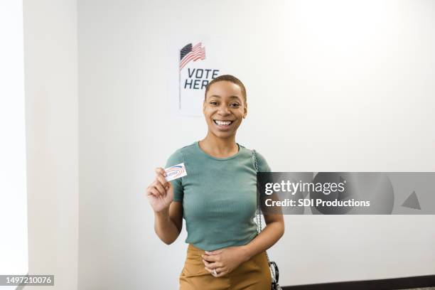 junge erwachsene freiwillige posiert für die kamera, während sie ihren "ich habe gewählt"-aufkleber hält - i voted sticker stock-fotos und bilder