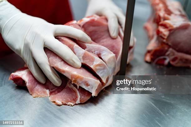 close up shot of butcher cutting a block of por with an electric saw - talhante imagens e fotografias de stock