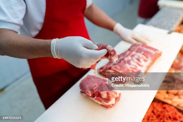 primo piano di un macellaio irriconoscibile che affetta un blocco di carne per un cliente al supermercato - butcher foto e immagini stock