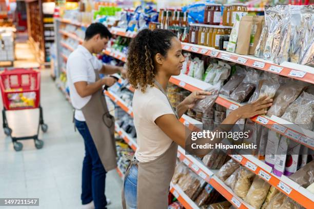 team of sales people working at the supermarket restocking the retail display - damstrumpor bildbanksfoton och bilder