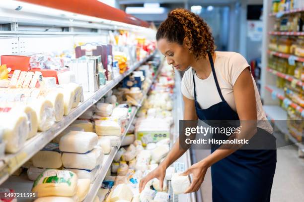 black saleswoman organizing the cheese in the refrigerated section at the supermarket - mejeriavdelning bildbanksfoton och bilder