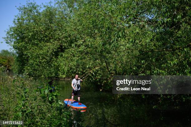 Man paddleboards along an overgrown scetion of the River Cam on June 09, 2023 in Cambridge, England. Heat health warnings have been issued across the...