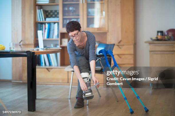 woman with broken leg adjusting her leg brace - woman in broken shoe heel stockfoto's en -beelden