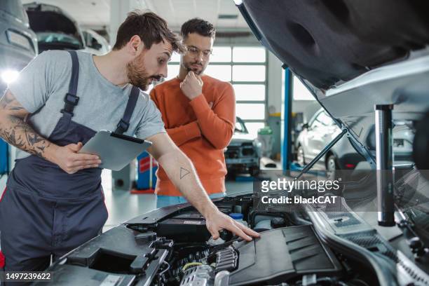 customer and automotive technician talking  about the car problem in a workshop - motor corp stock pictures, royalty-free photos & images