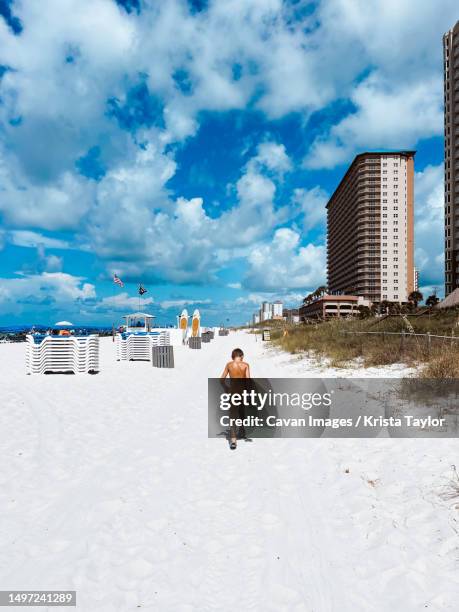 child walking down white sand beach on summer day - panama city beach imagens e fotografias de stock