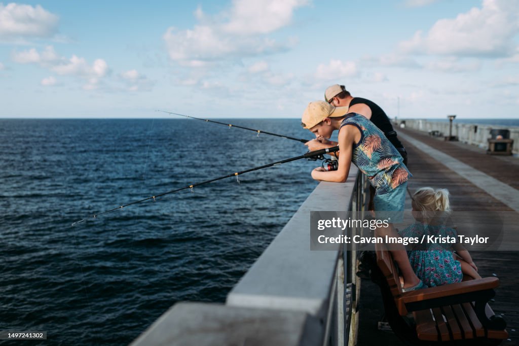 Family fishing off pier over ocean in Florida