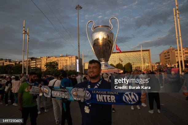 An Internazionale fan holds a scarf in front of a giant replica of the Champions League trophy in Taksim Square ahead of the UEFA Champions League...