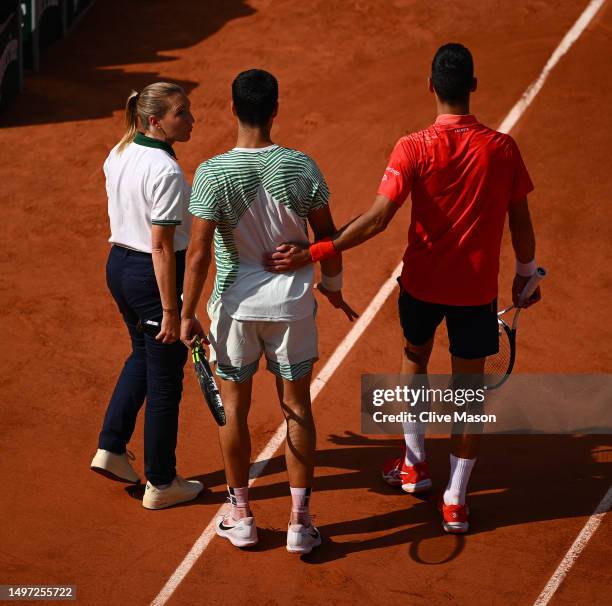 Carlos Alcaraz of Spain appears to be injured as he speaks to Novak Djokovic of Serbia during the Men's Singles Semi Final match on Day Thirteen of...