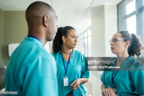 doctors talking in hospital corridor - nurse stockfoto's en -beelden