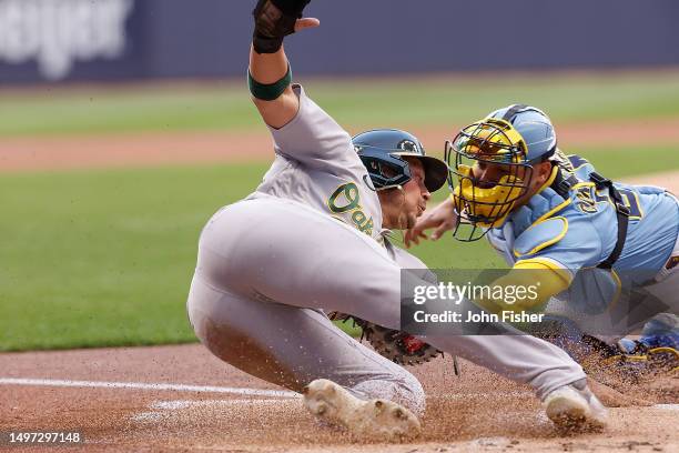Ryan Noda of the Oakland Athletics slides safely into home plate past the tag of William Contreras of the Milwaukee Brewers in the first inning at...