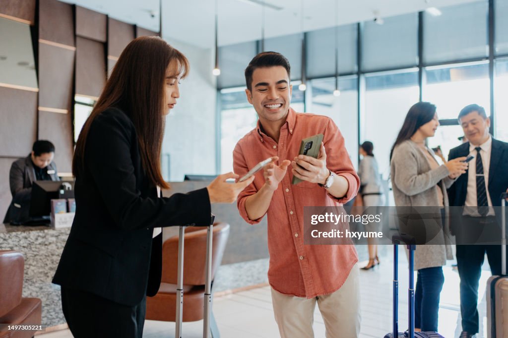 Asian business people using smartphone and having conversation at hotel lobby