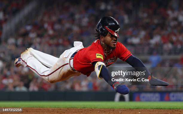 Ozzie Albies of the Atlanta Braves dives as he advances to third base on a single by Marcell Ozuna in the sixth inning against the Washington...