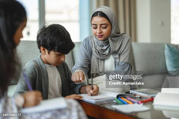 middle eastern mother helping her son with school work - middle eastern culture stock pictures, royalty-free photos & images