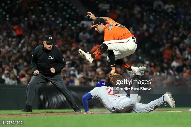 Casey Schmitt of the San Francisco Giants jumps over Matt Mervis of the Chicago Cubs as Mervis slides safely back into third base in the seventh...