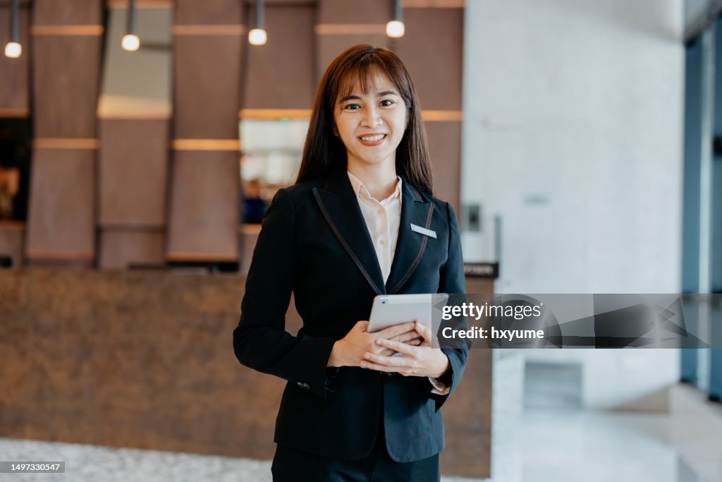 Asian female hotel manager smiling and looking at camera