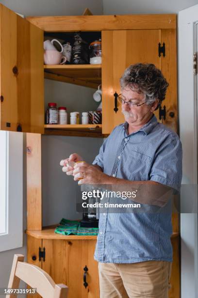 elderly man taking medication in home kitchen - pill counting stock pictures, royalty-free photos & images