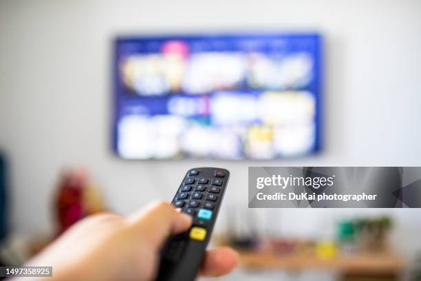 man holds a tv remote control - tv stockfoto's en -beelden