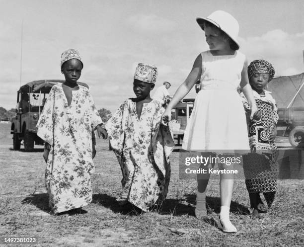 Elaine Bee, daughter of a Lancashire textile miller, with three Nigerian children, each in traditional dress, during a children's pageant in the...
