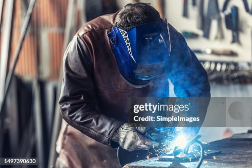 A professional welder welds a product with argon in a welding workshop.