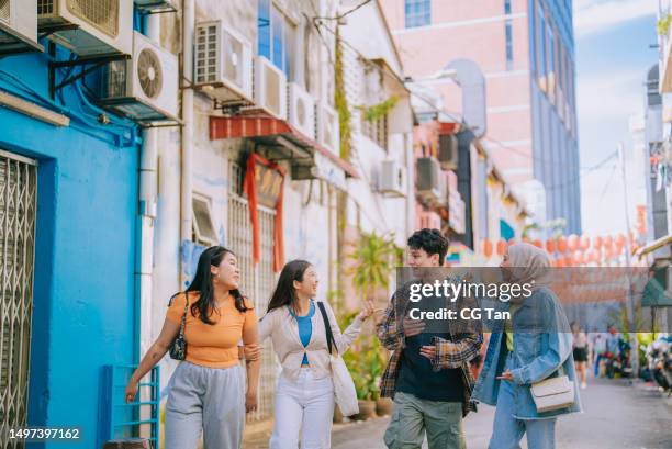 multiracial asian young friends enjoy walking in city street together - malaysian culture stock pictures, royalty-free photos & images