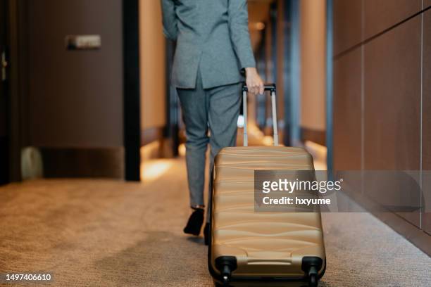 businesswoman with suitcase walking through hotel corridor - professional drag stock pictures, royalty-free photos & images