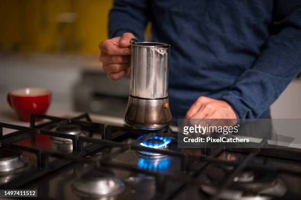 close up man lights flame on gas hob putting on the coffee pot - range of coffees stock pictures, royalty-free photos & images