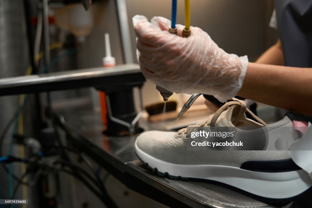 Operatore di lavaggio a secco donna che spruzza solvente su scarpe da ginnastica sporche