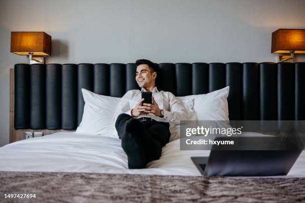 businessman using smartphone in hotel room - suitcase hotel stock pictures, royalty-free photos & images