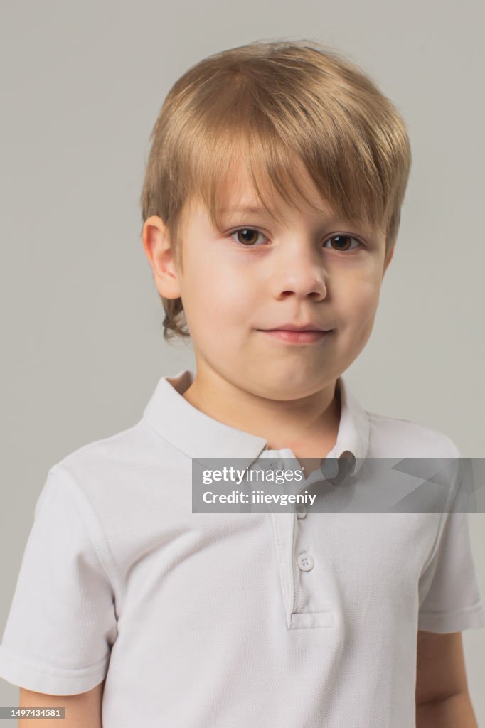 Chico rubio en camiseta y pantalón en estudio sobre fondo blanco. Moda infantil. Niñez