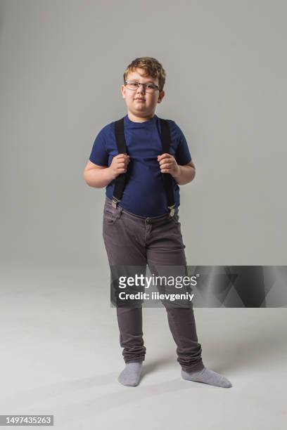 blonde boy in glasses and jeans with suspenders in studio on white background. child. childhood. schoolboy - child obesity stock pictures, royalty-free photos & images