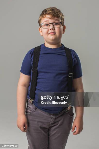 blonde boy in glasses and jeans with suspenders in studio on white background. child. childhood. schoolboy - chubby teen 個照片及圖片檔