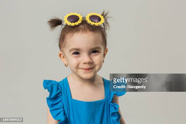 blonde baby girl in sunglasses and blue suit in studio on white background. child. childhood. hair bun hairstyle. summer fashion - summer hair bun stock pictures, royalty-free photos & images