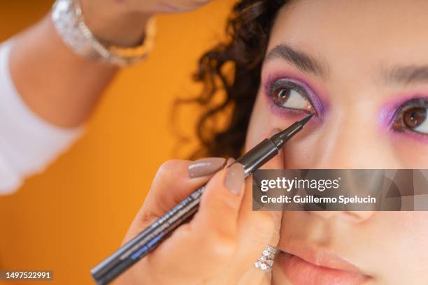 close up photo of a woman applying eyeliner to another woman - colorful eye liner stock pictures, royalty-free photos & images